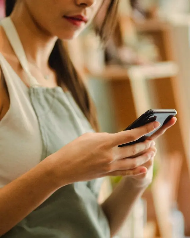 Una florista sostiene su teléfono en su tienda