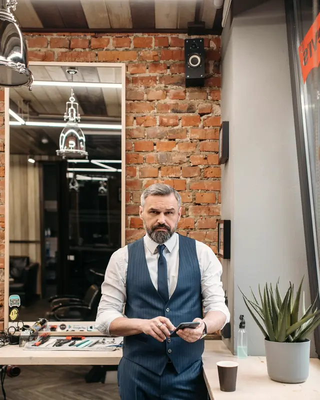 Un barbero revisa su teléfono en su barbería